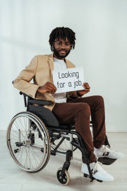 Beyaz arka planda tekerlekli sandalyede iş arayan afro-amerikan bir adam.