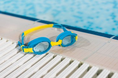 goggles near swimming pool with blue water  clipart