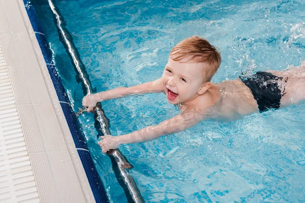 水泳プールのフラッターボードの近くで泳ぐ興奮した幼児の頭上の景色 — ストック写真