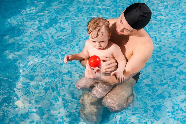 Entrenador Natación Gorra Natación Sosteniendo Pelota Cerca Niño Lindo Piscina —  Fotos de Stock