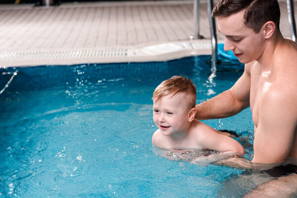 swim coach training happy toddler boy in swimming pool 