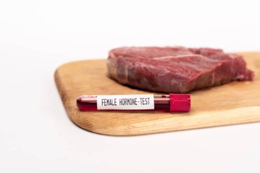 Selective focus of test tube with female hormone test on chopping board with raw meat isolated on white clipart