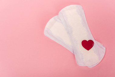 Pembe arka planda kağıt kalpli kadın pedlerinin üst görüntüsü