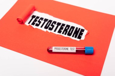 Testosteron harfleri beyaz harflerle izole edilmiş kırmızı kağıdın yanında progesteron kan örneğiyle test tüpünü kapat.
