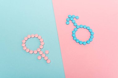 Mavi ve pembe arka planda hormonal haplardan kaynaklanan kadın ve erkek belirtileri yüksek açılı.