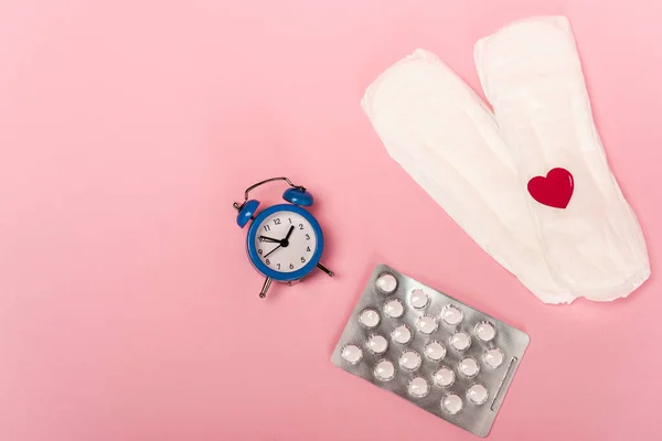 Vista Superior Almohadillas Femeninas Con Corazón Papel Píldoras Anticonceptivas Reloj —  Fotos de Stock