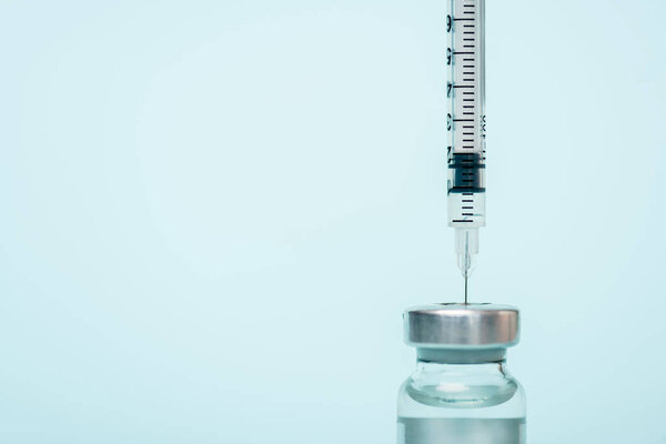 Close up view of jar of hormonal vaccine and syringe isolated on blue