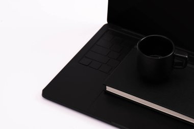 Siyah dizüstü bilgisayardaki defter ve kupa beyaza izole edilmiş. 