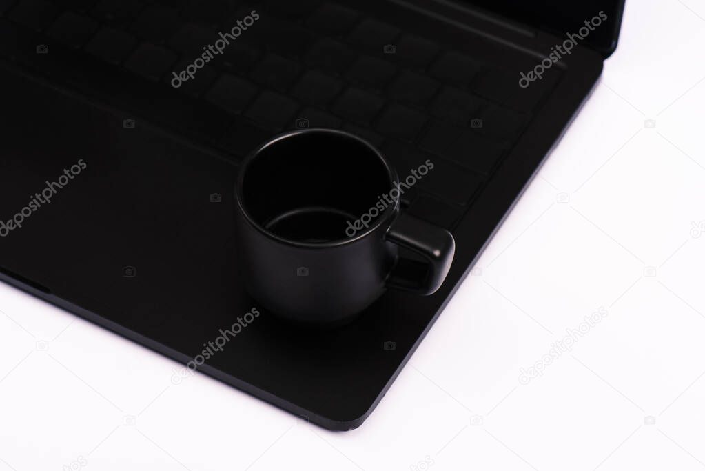 cup with drink on black laptop keyboard isolated on white 