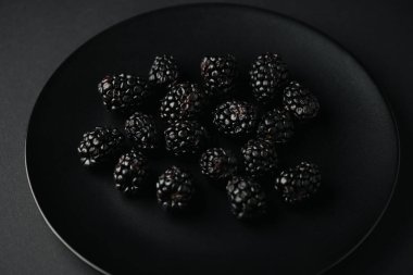 Siyah üzerine organik ve lezzetli böğürtlenli tabağın üst görüntüsü