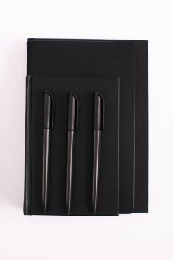 Siyah fotokopi kitaplarındaki kalemlerin beyaza izole edilmiş üst görünümü 