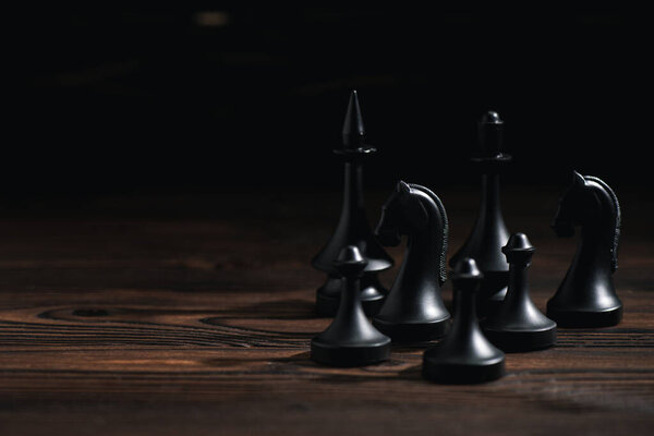 chess figures on wooden surface isolated on black 