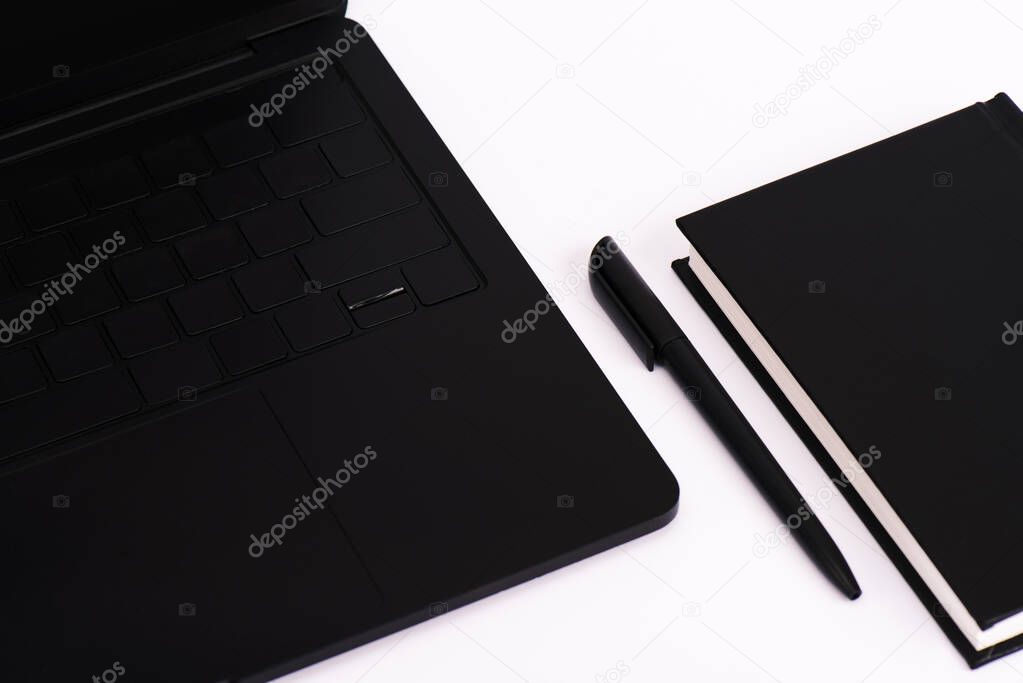 pen and notebook near modern laptop isolated on white 