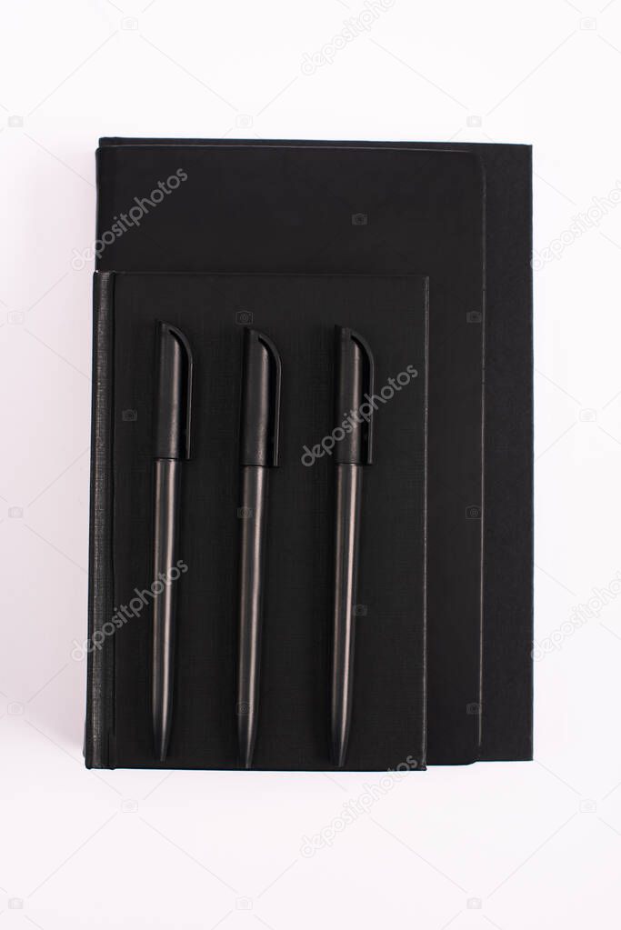 top view of pens on black copy books isolated on white 