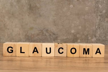 Glaucoma harfleri gri arka plandaki tahta masada küp şeklinde.
