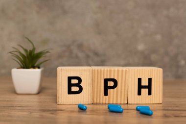 Bph harfli küplerin seçici odak noktası ve gri arkaplanda tahta masa üzerine bitki içeren haplar