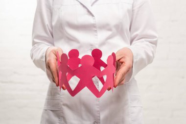Beyaz arka planda elinde kağıt figürler tutan doktor görüşü