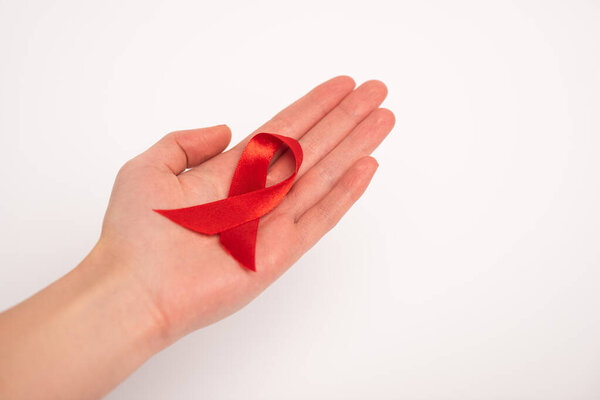 Обрезанный вид женщины, держащей в руках СПИД осознание красной ленты изолированы на белом
