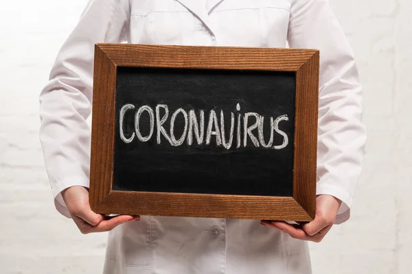 Cropped View Doctor Holding Chalkboard Coronavirus Lettering White Background — Stock Photo, Image