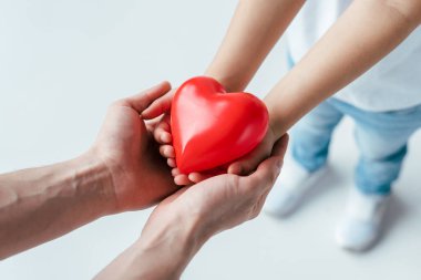 Evlat edinilmiş çocuk ve ebeveynin beyaz kalbe kırmızı kalp takması 