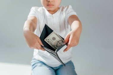 Gri nafaka konsepti üzerinde dolar banknotları olan cüzdan tutan Afrikalı Amerikalı çocuk manzarası. 