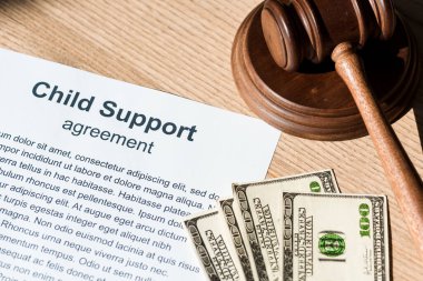 wooden gavel near document with child support agreement and dollar banknotes  clipart