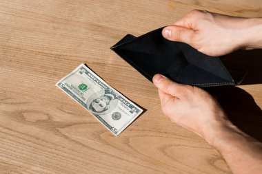 Bir dolarlık banknotun yanında boş cüzdan tutan adamın görüntüsü. 