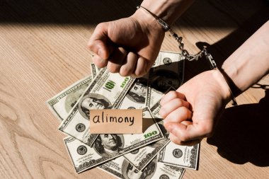Kağıdın yanındaki kelepçeli adamın nafaka kağıtları ve dolar banknotlarıyla görüntüsü.  