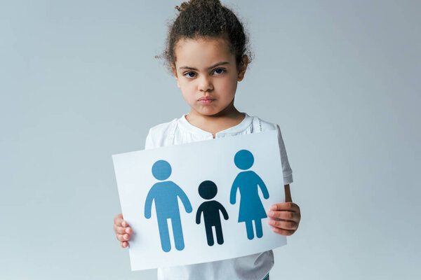 serious african american kid holding paper with drawn family isolated on grey, adoption concept 