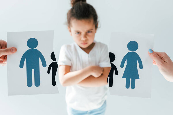 selective focus of man and woman holding ripped paper with separated family near displeased african american daughter isolated on white 
