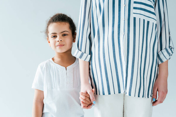 foster mother holding hands with adopted african american kid isolated on white 