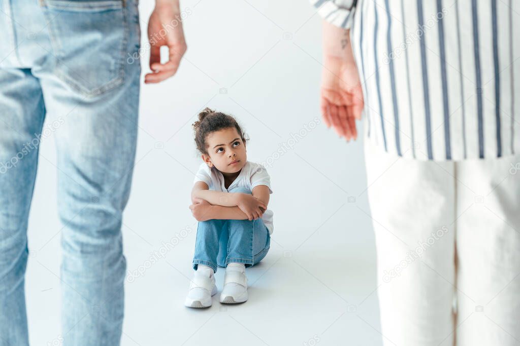 selective focus of african american kid sitting near foster parents on white 