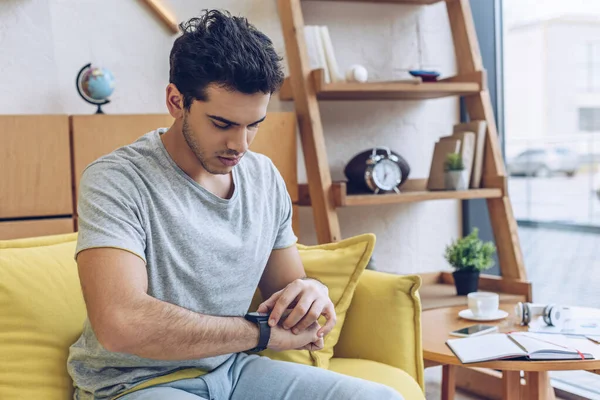 Mann Schaut Auf Armbanduhr Auf Sofa Wohnzimmer — Stockfoto