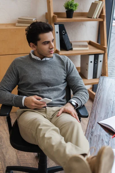 Foco Seletivo Empresário Pensativo Com Smartphone Colocar Pernas Mesa Escritório — Fotografia de Stock