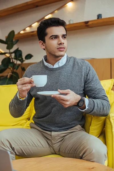 Egy Férfi Csészealjjal Egy Csésze Kávéval Kanapén — Stock Fotó
