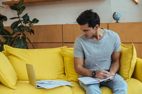 Freelancer Com Notebook Olhando Para Laptop Com Papéis Sofá Sala — Fotografia de Stock
