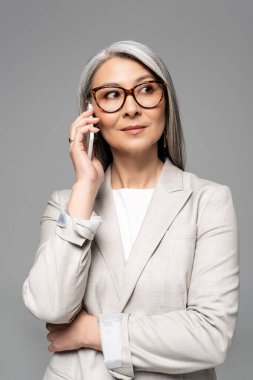 Gözlüklü, gri saçlı, akıllı telefondan konuşan Asyalı profesyonel bir iş kadını.