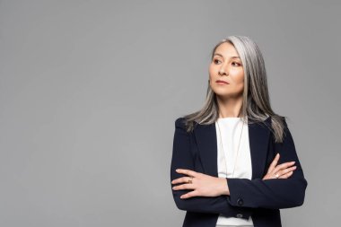 Gri saçlı, çapraz kollu, gri saçlı, kendine güvenen Asyalı stil sahibi iş kadını.