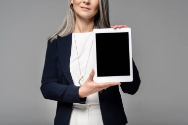 Gri ekranda boş ekran ile dijital tablet sunan iş kadınının kırpılmış görüntüsü 