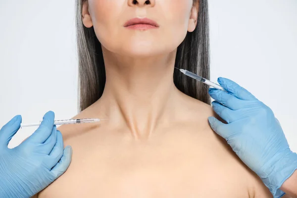 亚洲裸体妇女和医生戴着乳胶手套 拿着注射器 用灰色隔离的漂亮注射剂的剪影 — 图库照片