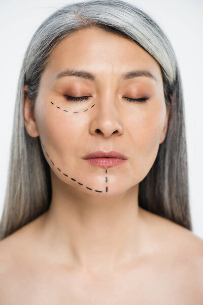 attractive nude asian woman with closed eyes and plastic surgery correction mark on face isolated on grey 