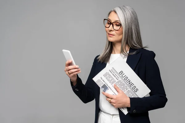 Confiante Asiática Empresária Óculos Usando Smartphone Segurando Jornal Negócios Isolado — Fotografia de Stock