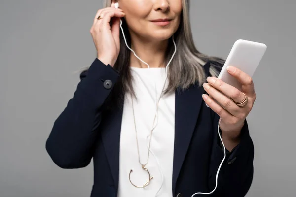 머리를 사업가가 이어폰 스마트폰으로 음악을 회색에 고립되어 — 스톡 사진