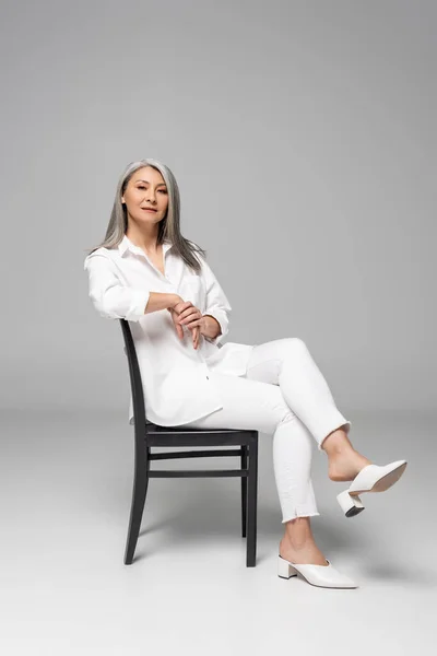 Krásná Sebevědomá Asijská Žena Šedými Vlasy Sedí Židli Šedé — Stock fotografie
