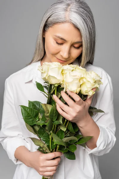 亚洲成年女子 头发灰白 手里拿着一束白玫瑰 花束是灰色的 — 图库照片