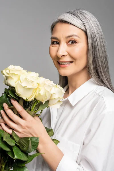 アジア人女性の笑顔と白髪持ちの花束グレーに孤立した白いバラ — ストック写真