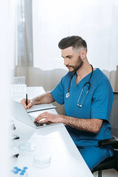 专心致志的医生在笔记本电脑上打字时的写作重点 — 图库照片