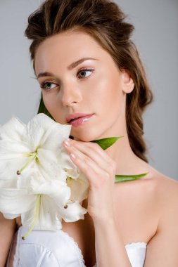 Gri renkte beyaz çiçeklere dokunan genç ve güzel bir kadın. 