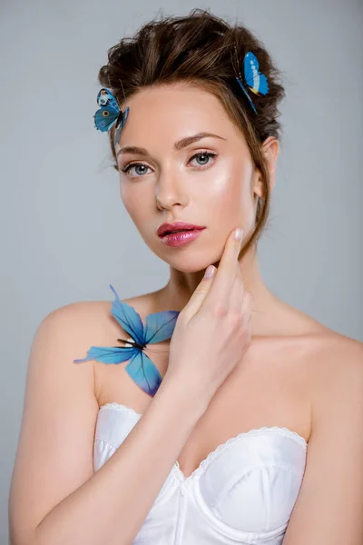 beautiful girl with decorative butterflies touching face isolated on grey