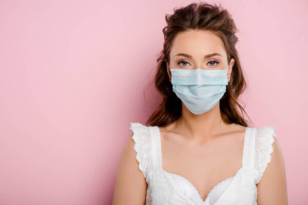 young woman in medical mask standing on pink